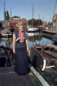852320 Afbeelding van een vrouw in klederdracht in de haven van Spakenburg.